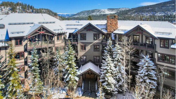 A multi-story hotel with a ski lift in the background, surrounded by snow-covered trees.