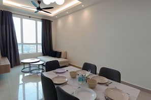 Un espace repas moderne avec une table dressée pour quatre personnes, un canapé et un ventilateur de plafond.