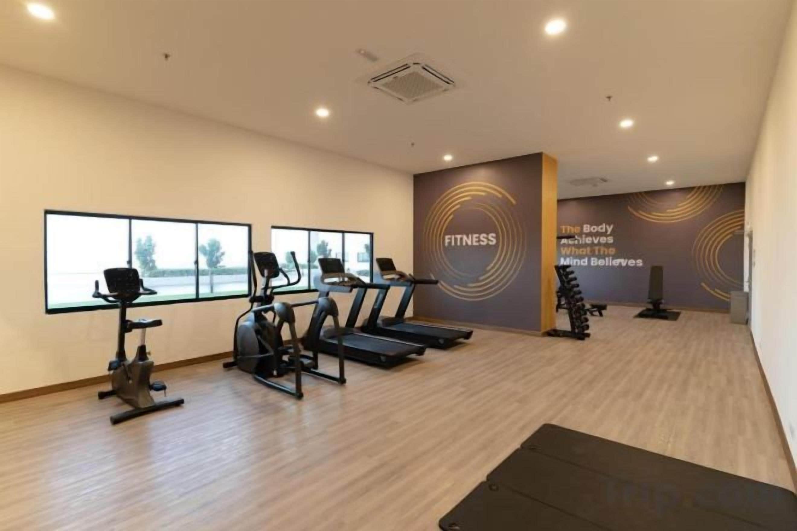 A fitness center with treadmills, stationary bikes, and a wall with motivational text.