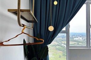 Una habitación con vistas a través de una ventana, una lámpara colgante y un perchero.
