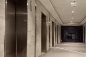A corridor with elevators and doors, leading to a darkened room. - Golden Bridge Business Hotel (Phnom Penh)