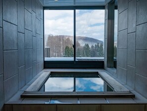 A modern interior with a large window, a wooden bench, and a view of a snowy landscape.