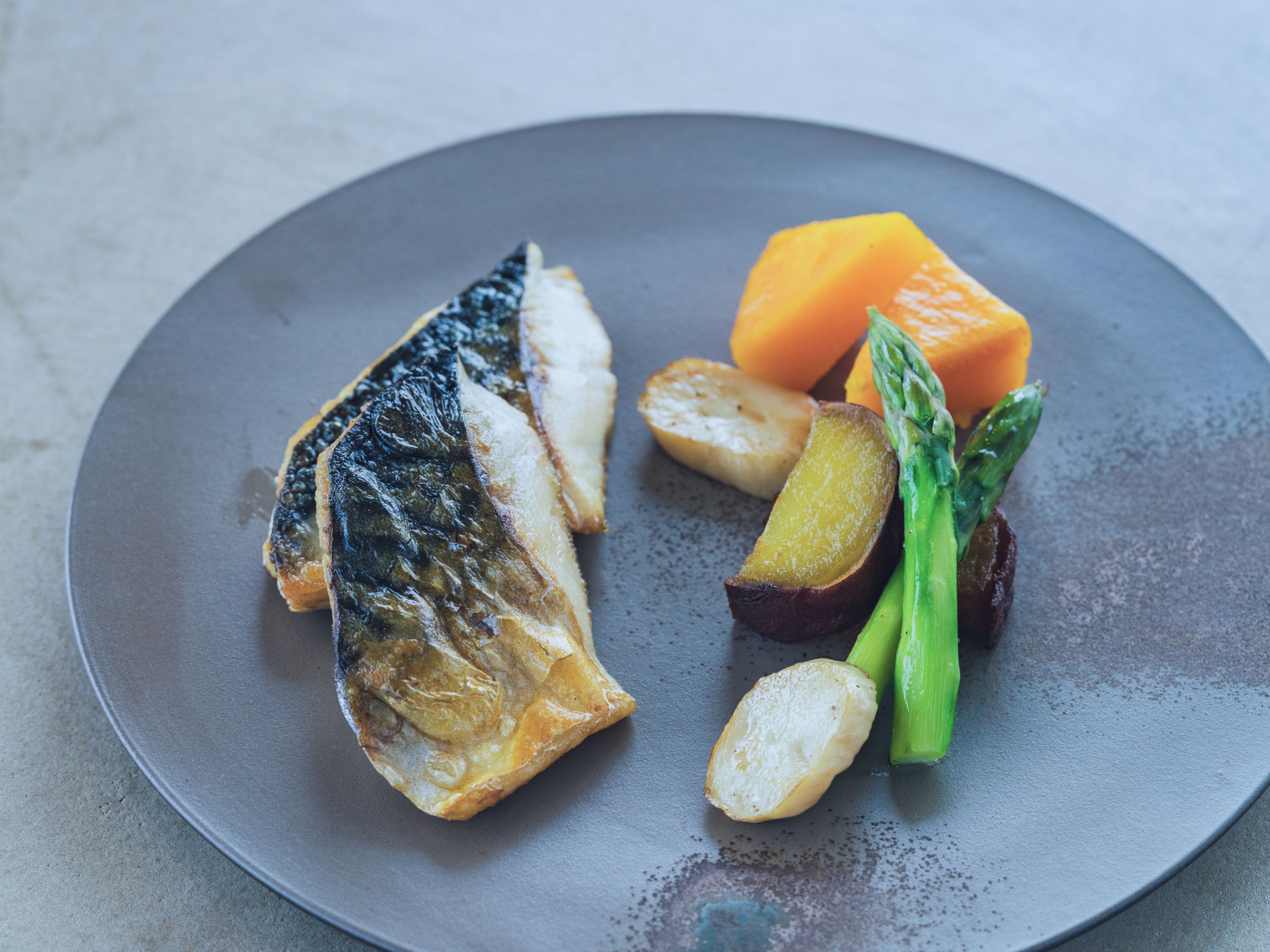 A plate with grilled fish, potatoes, and asparagus.