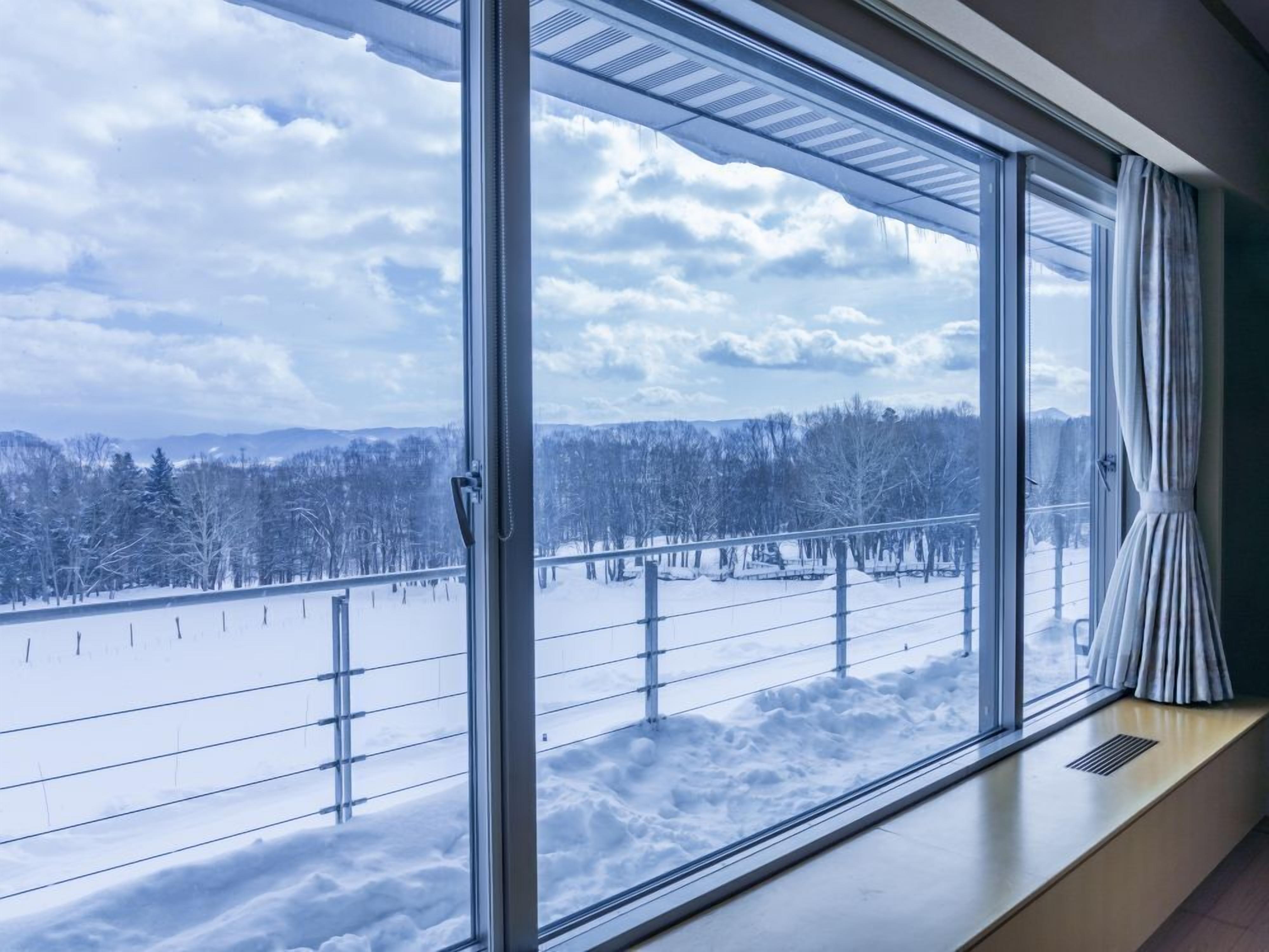 A room with a large window overlooking a snowy landscape.
