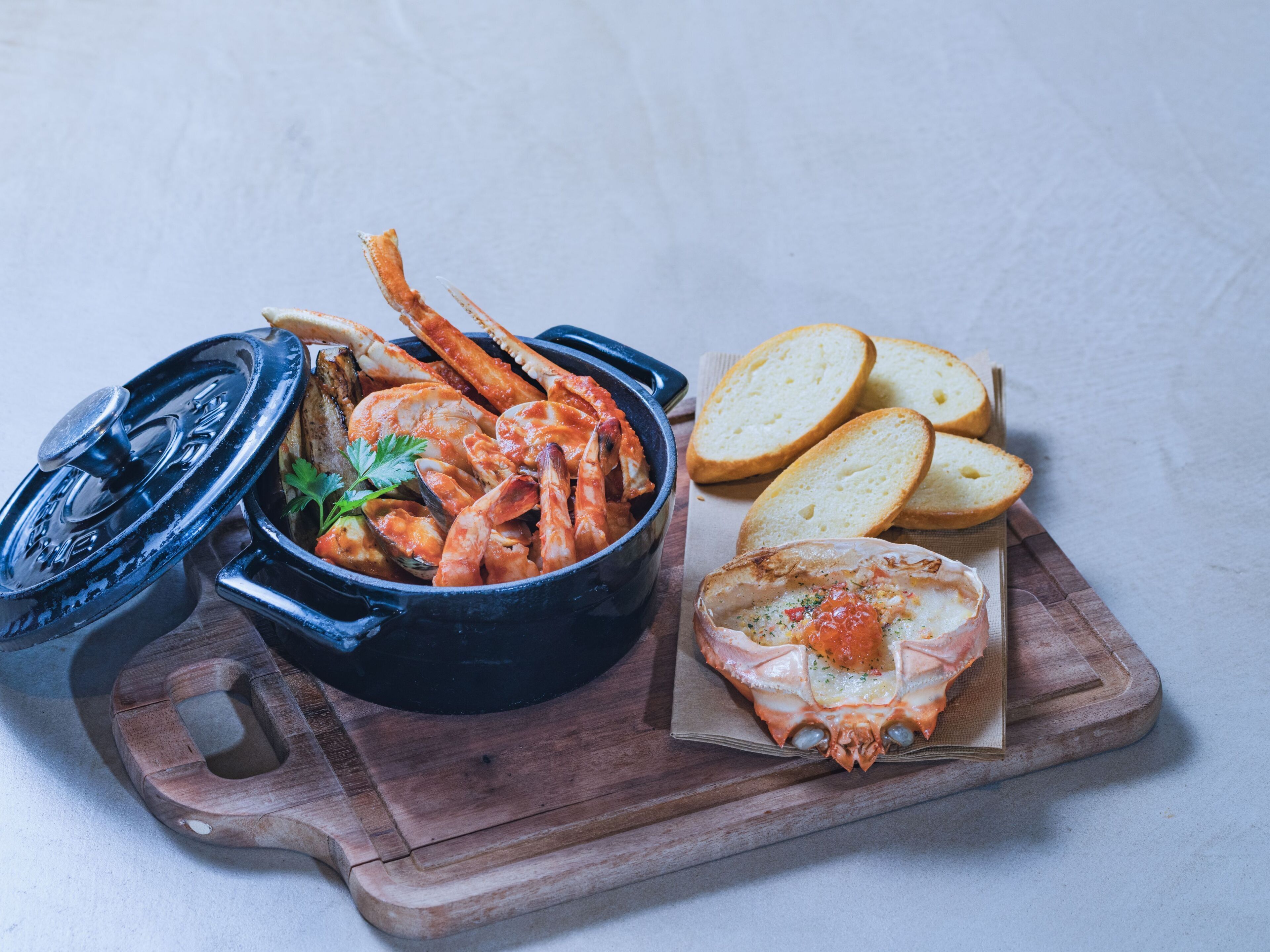 A seafood dish with bread on a wooden board.