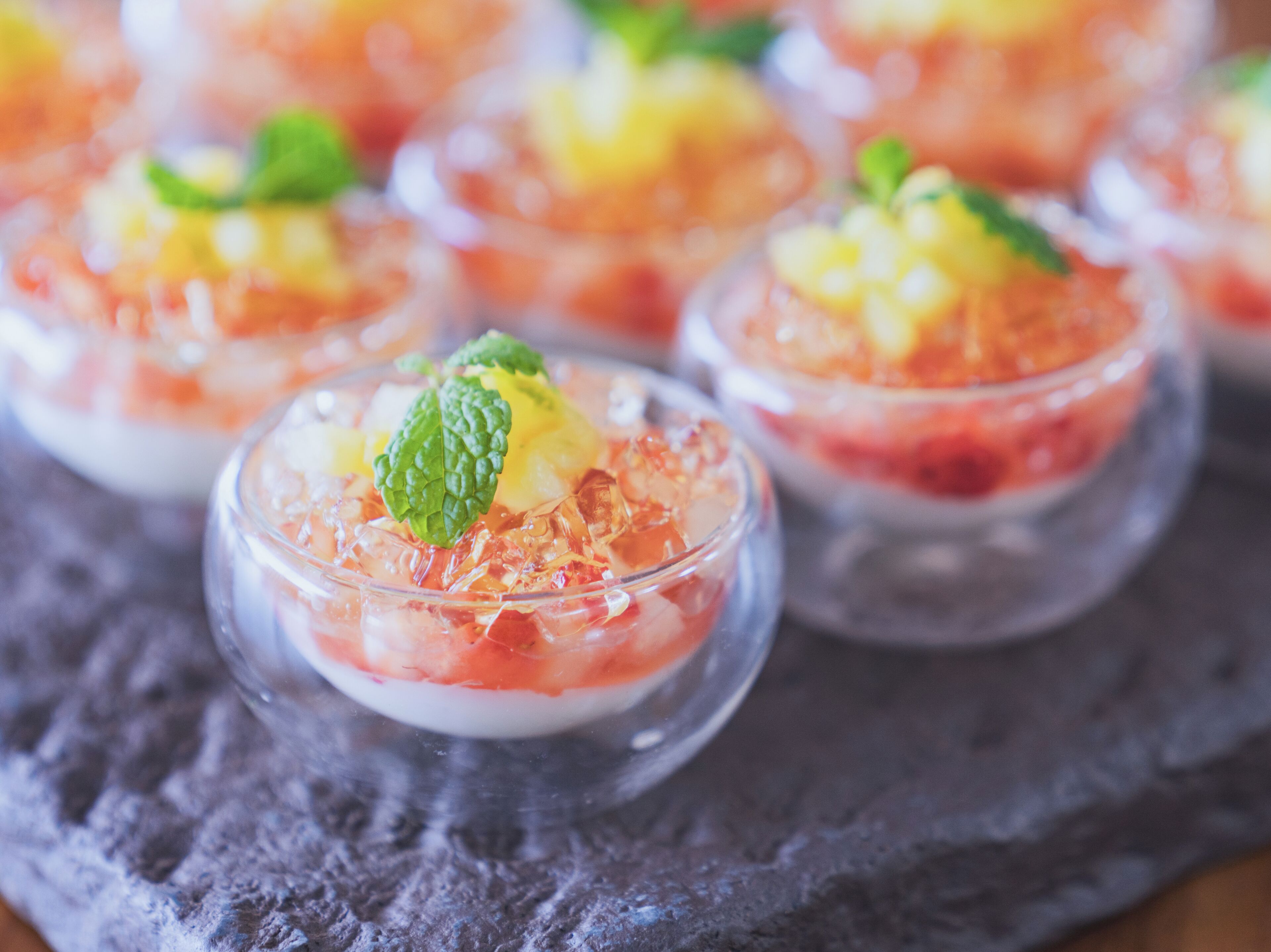 A dessert with fruit and mint garnish in a clear glass.