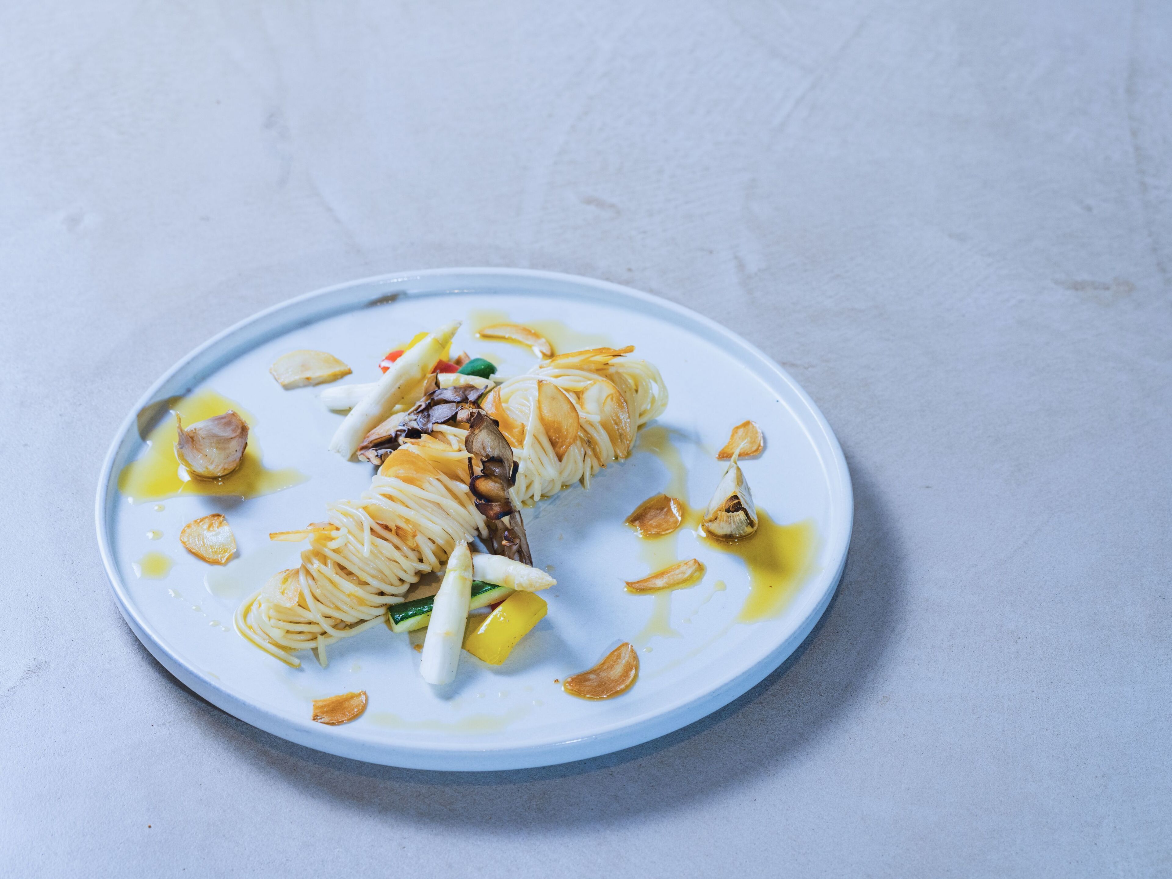 A plate with a rolled dish, possibly a sushi roll, garnished with garlic and vegetables.