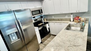 Une cuisine moderne dotée d’appareils électroménagers en acier inoxydable, de meubles blancs et d’un plan de travail en granit.