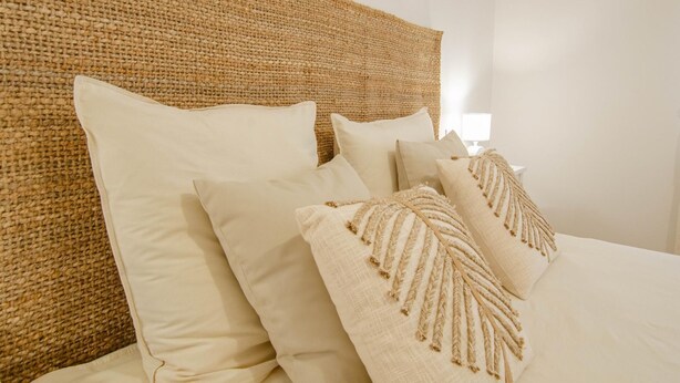 A bed with white linens and multiple pillows, including a decorative one with tassels.