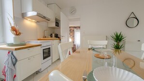 A modern kitchen with white cabinets, a wooden countertop, and a dining area with a glass table set for two.
