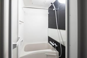 A bathroom with a bathtub, a shower, and a towel rack.