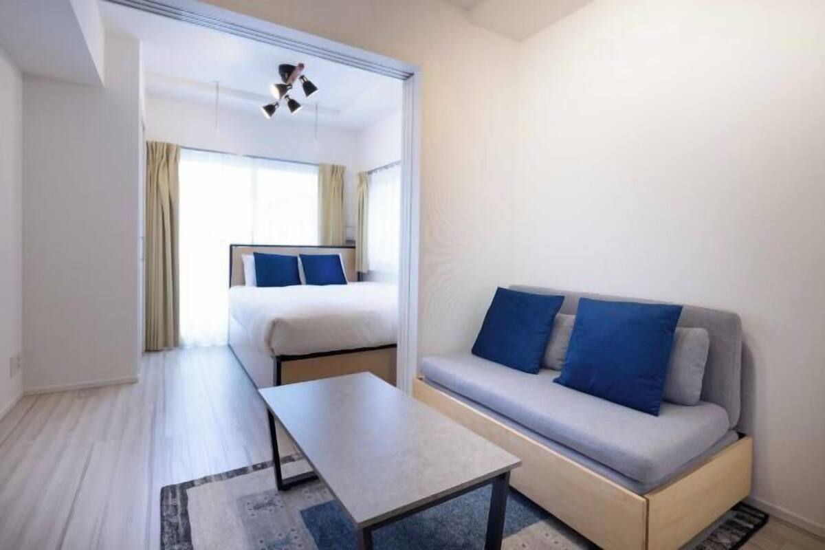 A hotel room with a bed, a sofa, a table, and a view of the outdoors.