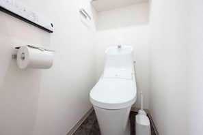 A white toilet with a roll of toilet paper on the wall, a bidet, and a small trash bin. - Renaissance Court Jiyugaoka (Tokyo)