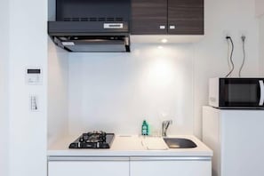 Una cocina compacta con estufa a gas, microondas y pileta.