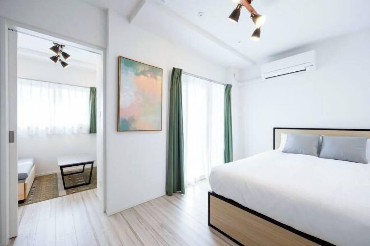 A modern hotel room with a large bed, a sofa, and a view of the city.