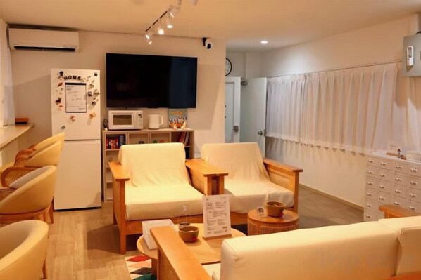 Un espace de vie compact comprenant un téléviseur à écran plat, un réfrigérateur, un four à micro-ondes et un coin repas avec des chaises et une table.