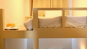 Ein Hotelzimmer mit einem Etagenbett, einem Nachttisch mit Lampe und einem Vorhangfenster.