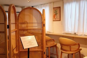 Une pièce comprenant un comptoir d’accueil, un espace détente avec des fauteuils et une fenêtre avec des rideaux.