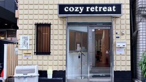 Ein Gebäude mit einem Schild, auf dem "cozy retreat" steht, und einem Glastür-Eingang.