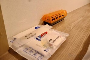Un tren de juguete sobre una superficie de madera, junto a un paquete de productos dentales.