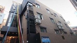 Un immeuble à plusieurs étages, doté d’une architecture moderne, qui se distingue par un escalier imposant, des unités de climatisation et une signalétique bien visible.