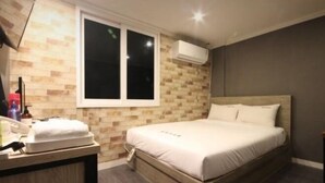 Une chambre d’hôtel équipée d’un lit, d’une fenêtre, d’un bureau avec un téléphone et d’un appareil de climatisation.