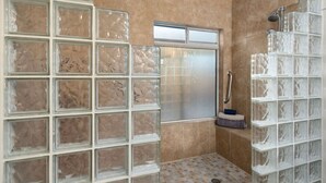 A bathroom with a glass block wall, a shower with a glass enclosure, and a tiled floor.