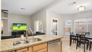 A modern kitchen with granite countertops, a dishwasher, and a dining area with a table and chairs.