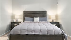 A bedroom with a large bed, two bedside tables, and a nightstand with a lamp.
