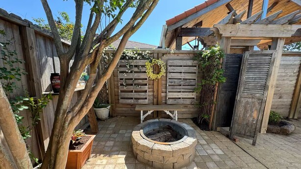 A backyard with a fire pit, wooden fence, and potted plants. - The Apartment of GRACE! (Corpus Christi)