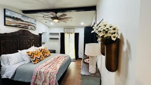 A bedroom with a bed, a ceiling fan, a nightstand, a lamp, and a wall-mounted flower vase. - The Apartment of GRACE! (Corpus Christi)