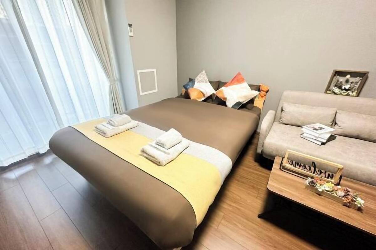 Een moderne hotelkamer met een groot bed, een bank en een klein tafeltje.