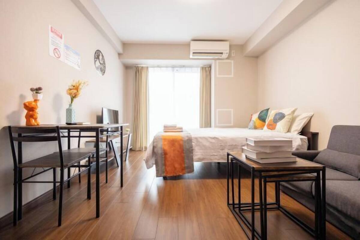 Hotelkamer met een bed, bureau, stoel, bank, televisie en een airconditioning.
