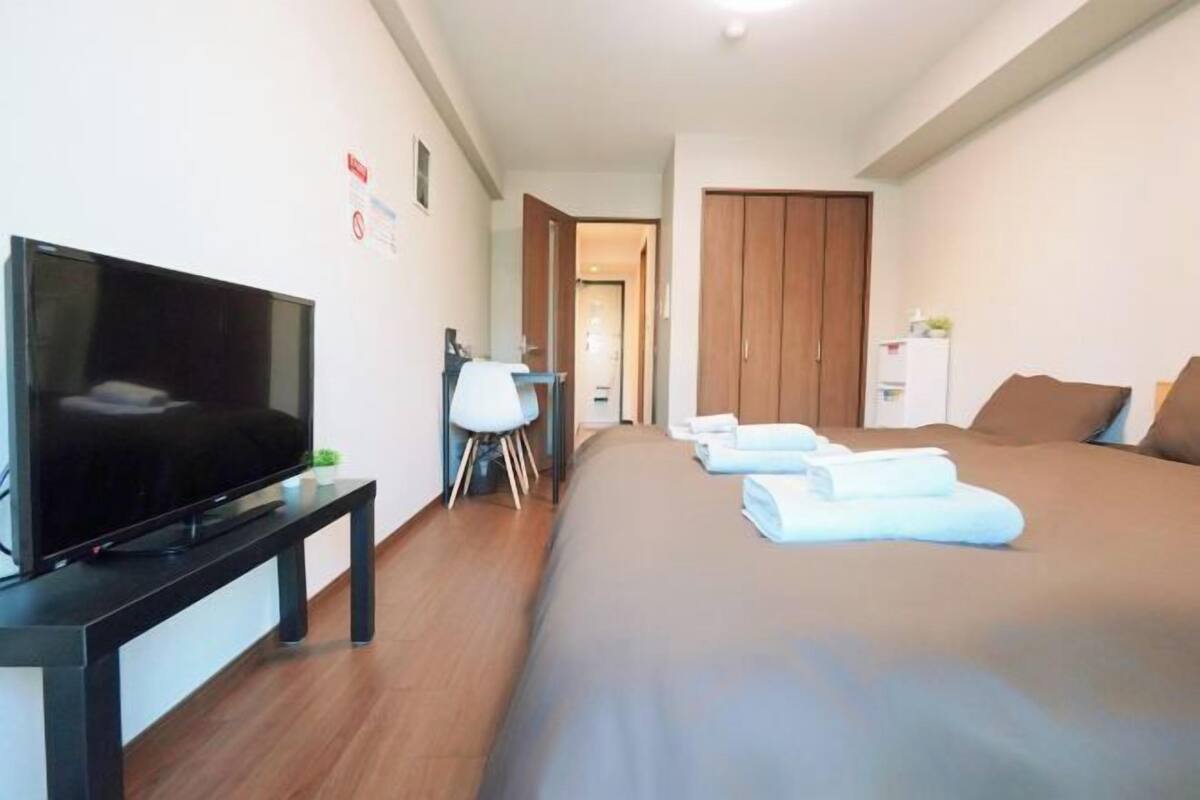 Een hotelkamer met een bed, een televisie op een standaard, een bureau en een kledingkast.