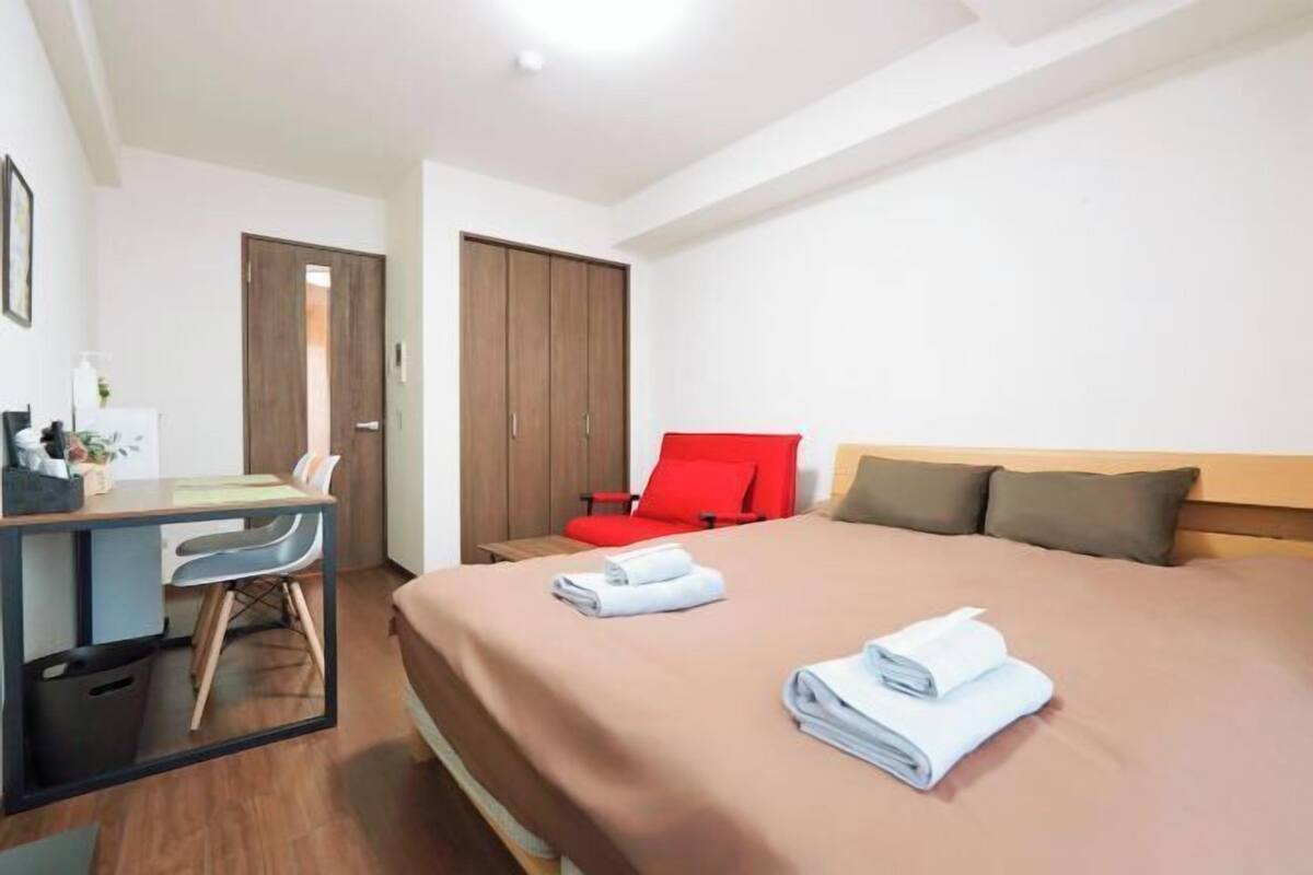 Een hotelkamer met een bed, een bureau, een stoel en een garderobe.