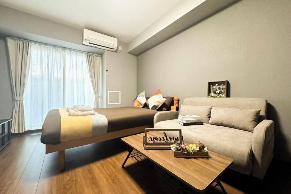 Een moderne hotelkamer met een bed, een bank en een klein houten tafeltje met een decoratief object.