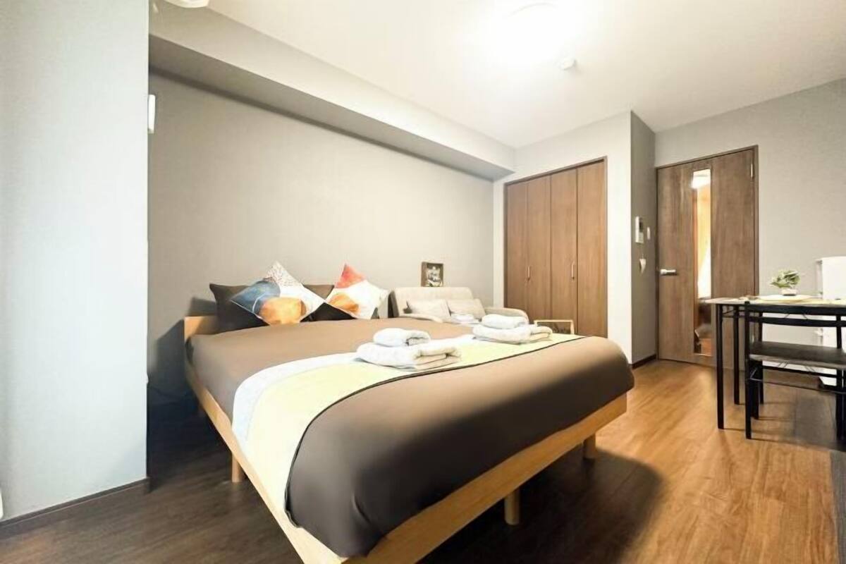 Een moderne hotelkamer met een bed, een klein tafeltje en een kledingkast.