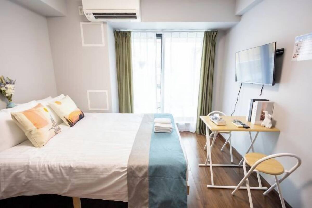 Een hotelkamer met een bed, bureau, stoel, televisie en een raam met gordijnen.