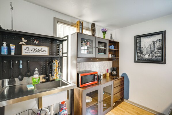 A compact kitchen with a microwave, coffee maker, and storage cabinets.