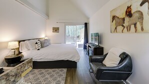 A bedroom with a large bed, a leather armchair, a desk, and a painting of horses.
