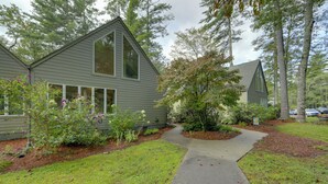 A two-story house with a sloped roof, a front yard with a pathway, and a small garden area.