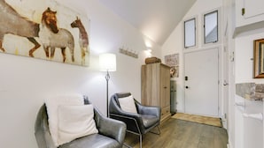 A room with two leather chairs, a white lamp, a wooden cabinet, and a door with a mirror.