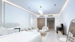 A modern hotel room with a large bed, a sofa, a small round table, and a TV. - Relaxing ST Getaway Balcony, Pool & Gym Access (Dubai)