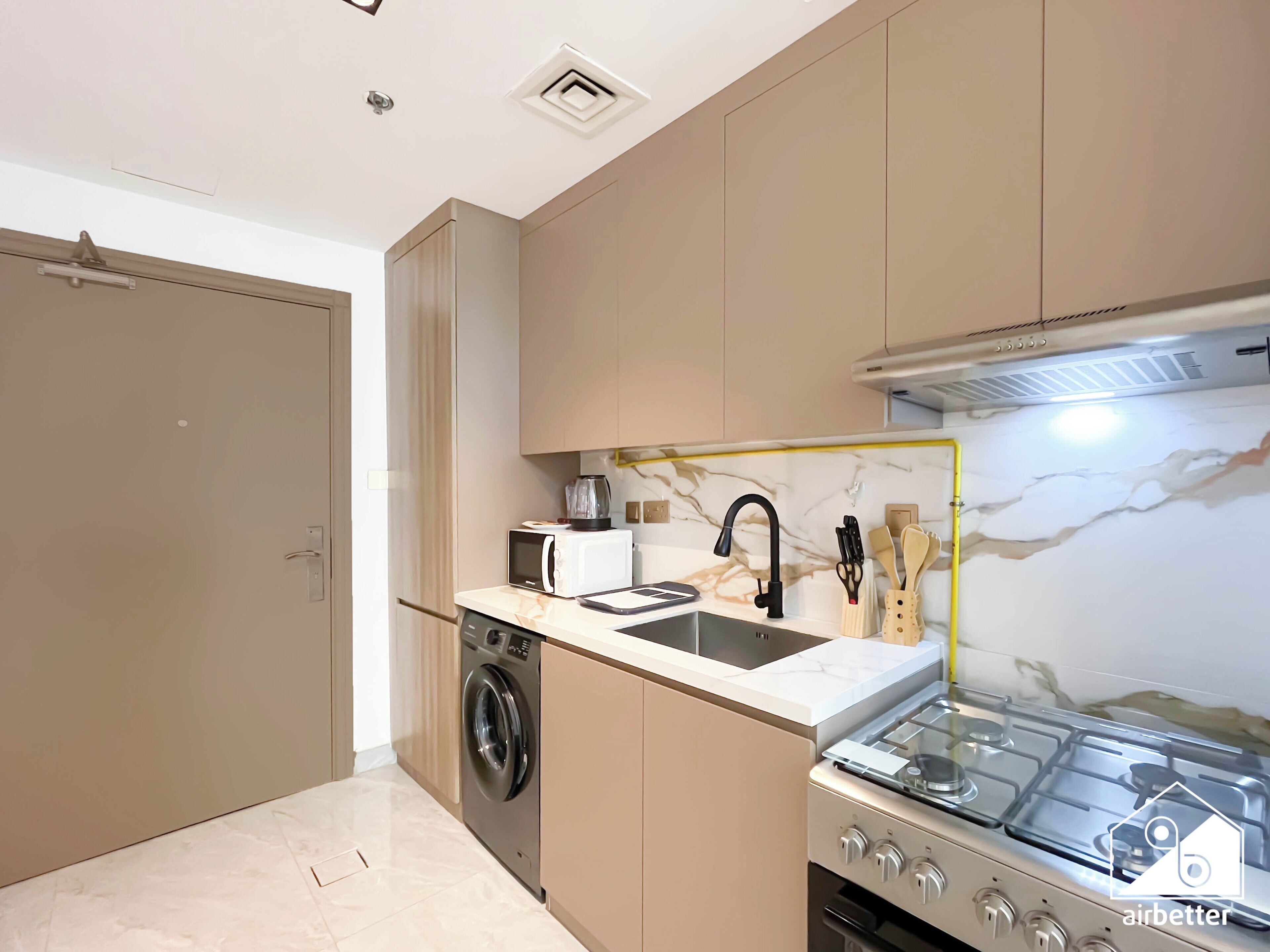 Una cocina compacta con lavadora, estufa y microondas.