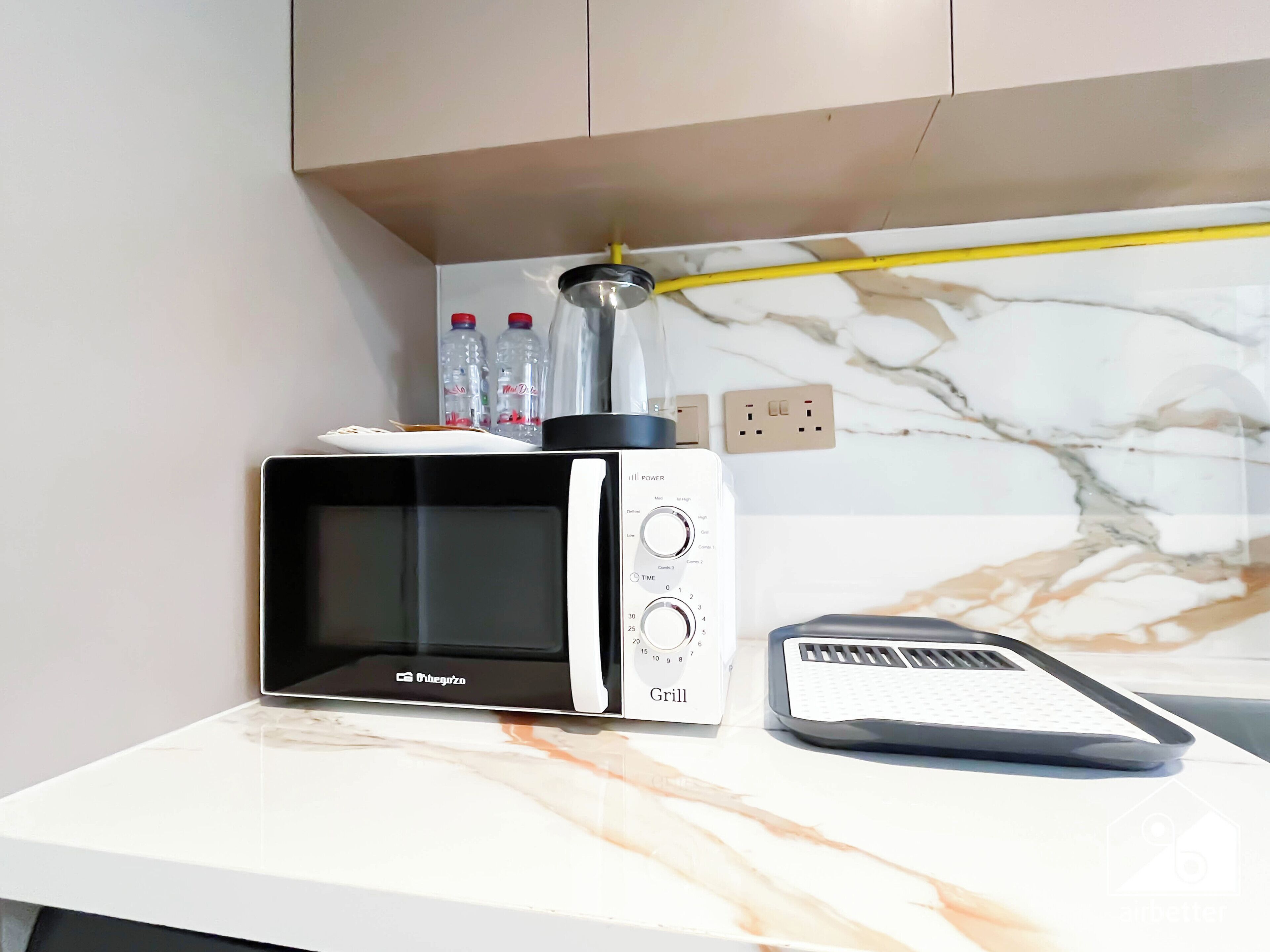 Une cuisine équipée d’un four à micro-ondes, d’une bouilloire et d’un support pour la bouilloire.