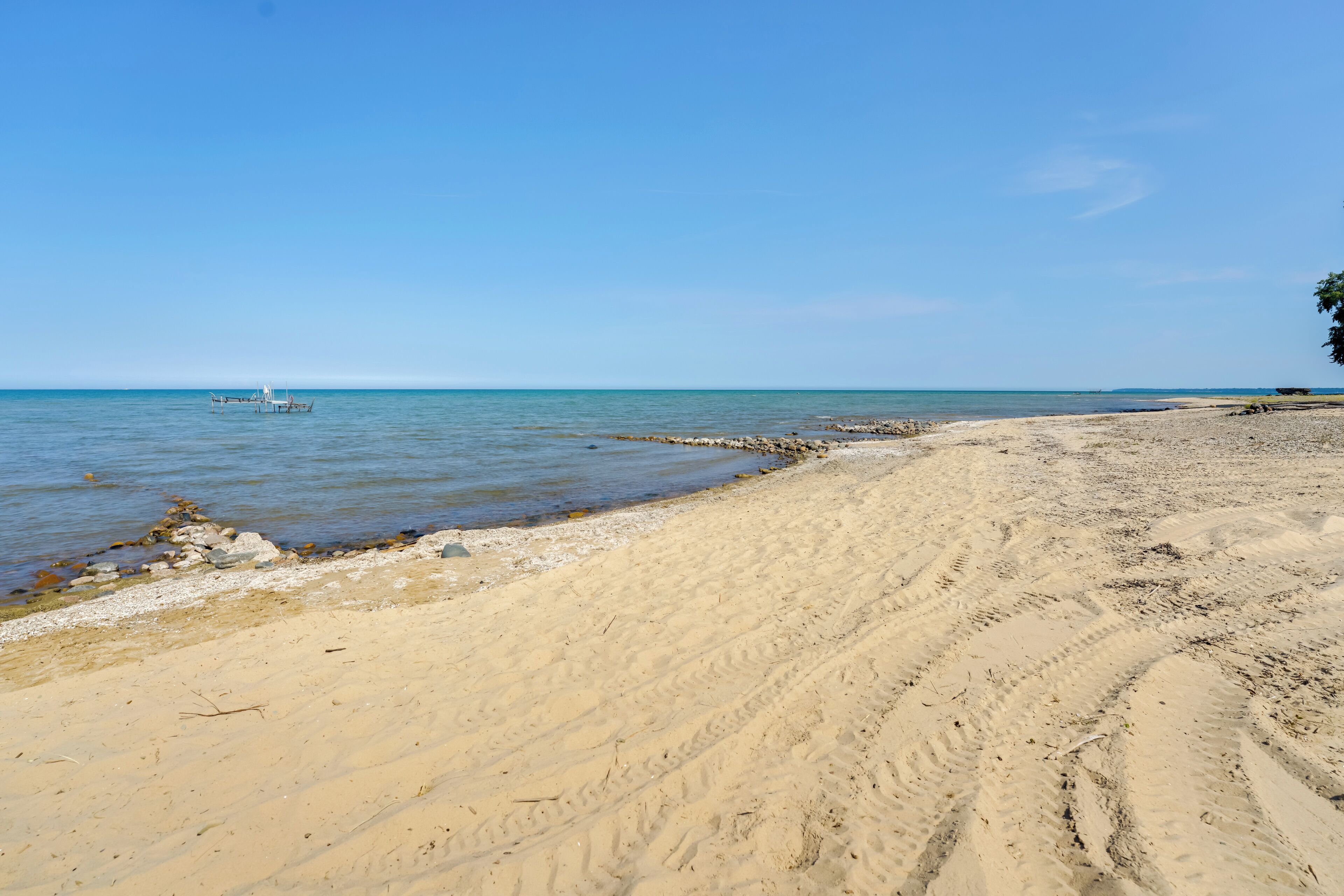 Una playa arenosa con cielo azul despejado y mar tranquilo.