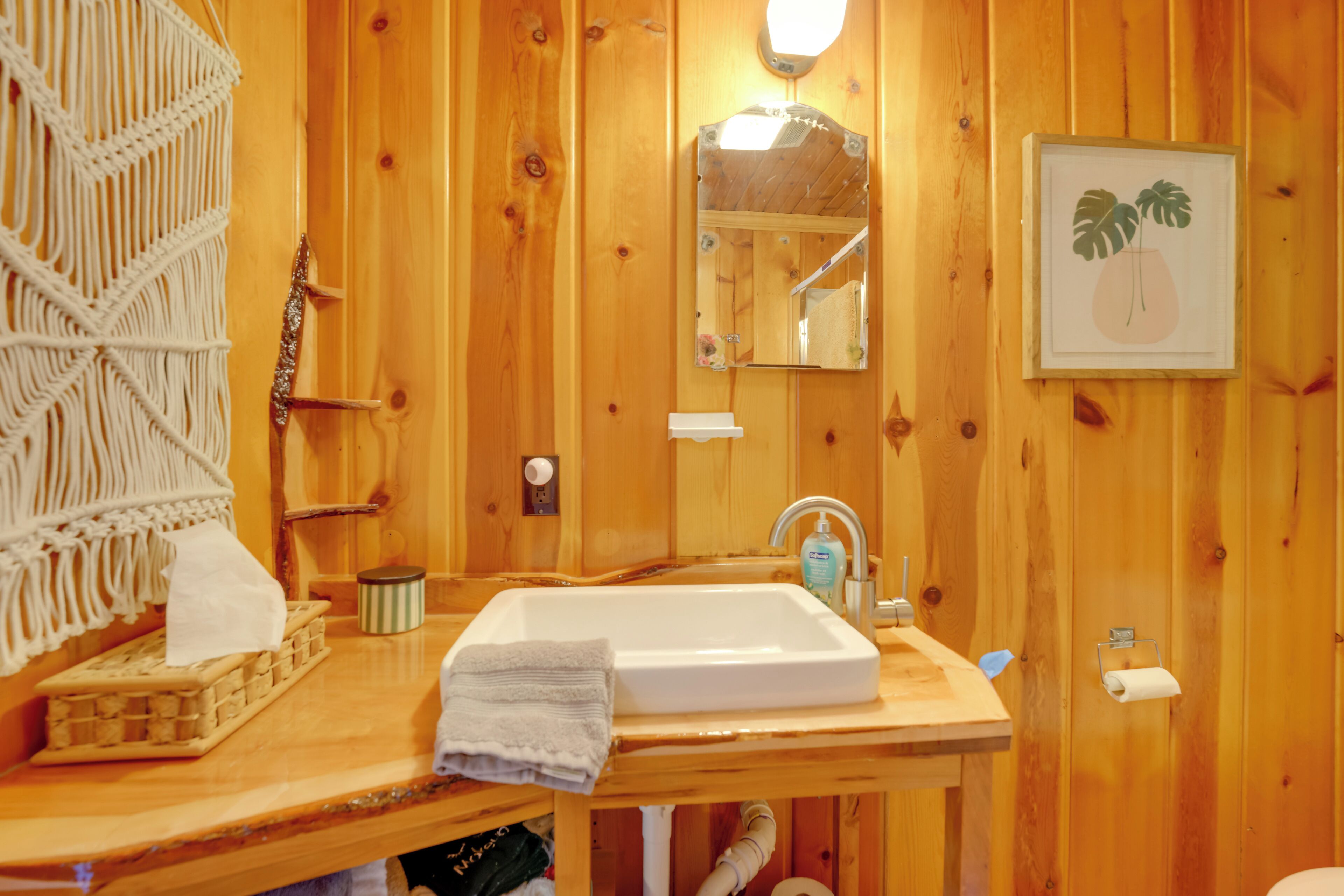 A wooden bathroom with a sink, mirror, and towel rack.