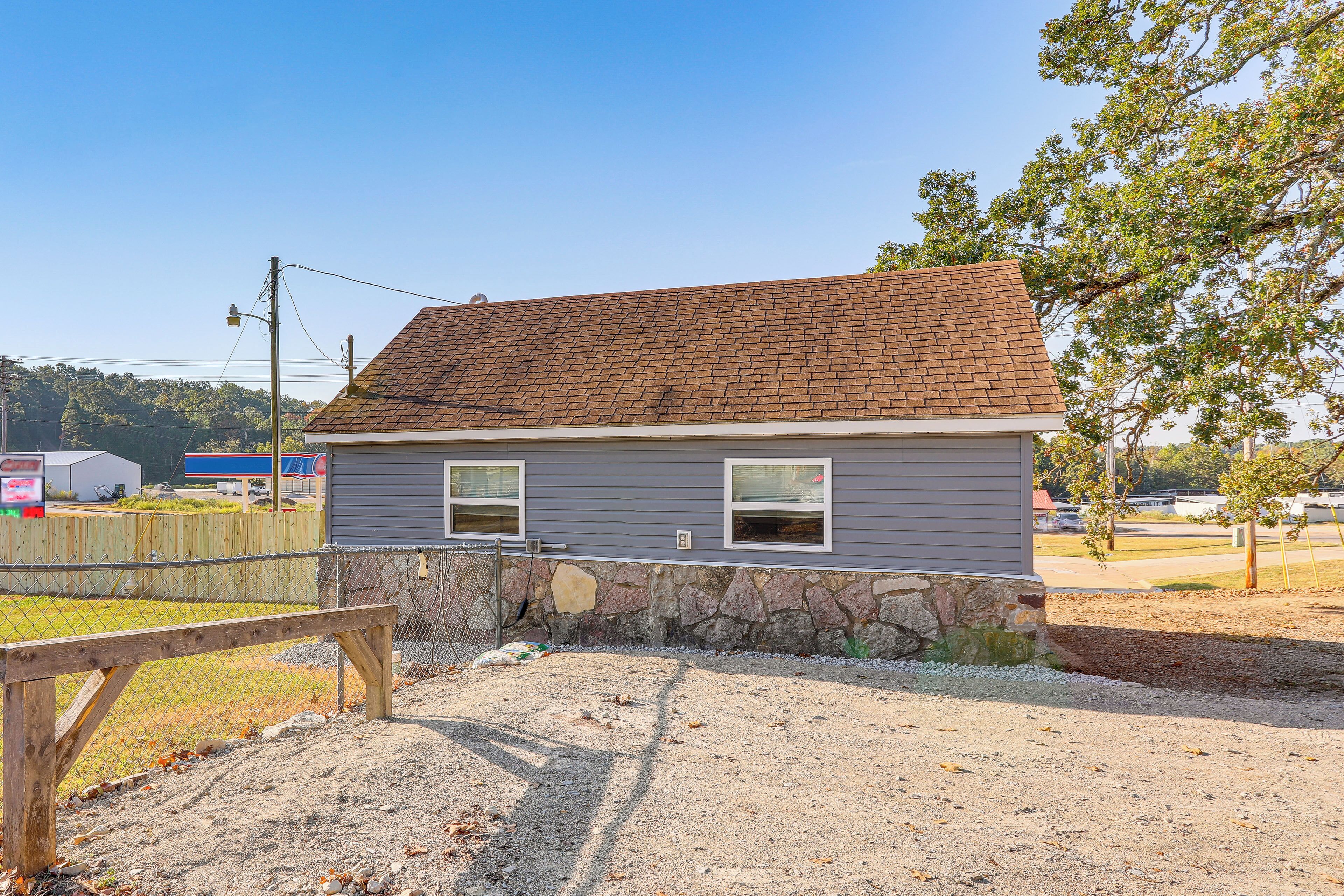 A single-story house with a stone foundation and a brown shingle roof.