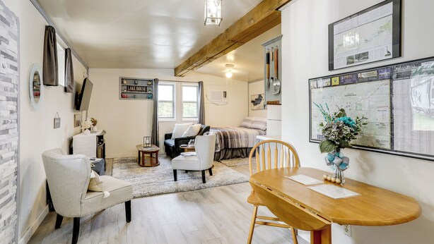 A cozy living room with a wooden dining table, a sofa, and a coffee table. There are framed pictures on the walls and a map on the wall. - Fish, Boat & Hike: Norfork Lake Studio Near Marina (Mountain Home)