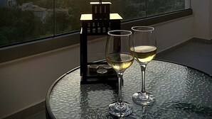 A balcony with a glass table, two wine glasses, and a candle holder with candles. - LefkoParga luxury Suites  (Parga)